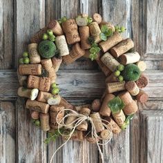 a wreath made out of wine corks with green plants and leaves on the front