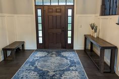 a large blue rug is in front of a wooden door and two benches on either side