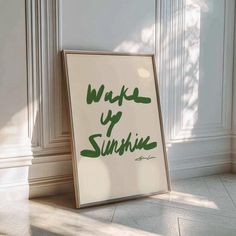 a sign that says wake up sunshine in green ink on a white wall next to a window