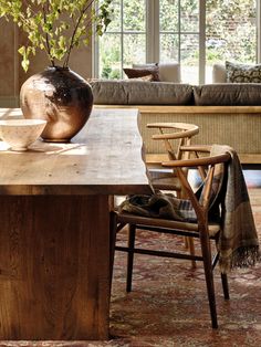 a wooden table topped with a vase filled with flowers next to a chair and couch