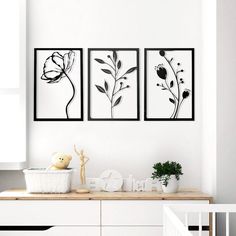 three black and white paintings on the wall above a dresser