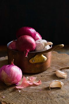 red onions and garlic in a bowl on a wooden table