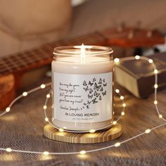 a candle sitting on top of a wooden table next to a string of lights and a guitar