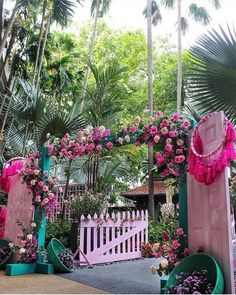 the entrance to a tropical garden with pink flowers and greenery on it's sides