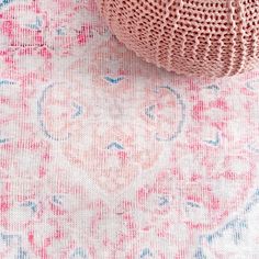 a pink and blue rug on top of a white tablecloth with an intricate design