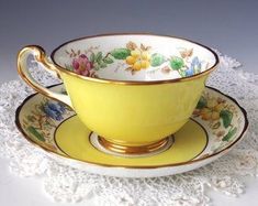 a yellow tea cup and saucer on a doily