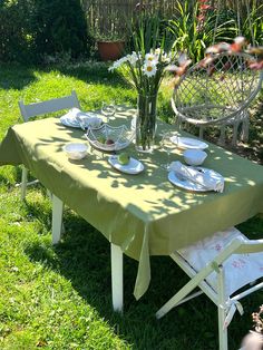 a table with plates and flowers on it in the grass next to a chair outside