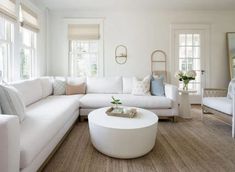 a living room filled with white furniture and lots of windows