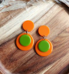 Add a touch of nostalgic charm to your look with these stunning 1960s style retro earrings which have been handmade in resin. They feature a vibrant colour block design in orange and apple green and their geometric shape adds a modern twist to their vintage-inspired appeal.  Perfect for any occasion, these earrings are sure to make a bold and stylish statement and they will make beautiful and unique gifts for lovers of mid century fashion. They measure 55mm x 30mm and they are finished with stai Retro Handmade Orange Earrings, Handmade Retro Orange Earrings, Mid-century Handmade Earrings As Gift, Handmade Mid-century Style Earrings For Gifts, Handmade Mid-century Earrings As Gift, Retro Green Drop Earrings, Handmade Vintage Resin Earrings, Retro Handmade Earrings For Party, Handmade Retro Earrings For Party