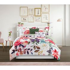 a bed with flowers on it in a room next to pictures and chairs, including a pink chair