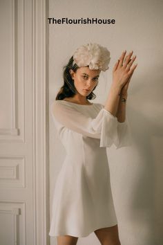 a woman wearing a white dress and flower in her hair is posing for the camera