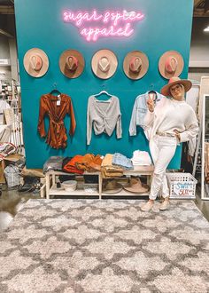 a woman standing in front of a display of hats and clothing