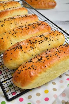 four loaves of bread sitting on a cooling rack with sprinkled black sesame seeds