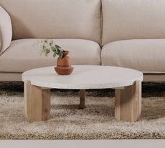 a white coffee table sitting in front of a beige couch on top of a shaggy rug