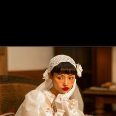 a woman in a white wedding dress sitting on a chair with her hands folded over her face