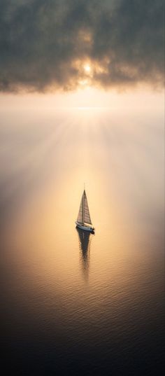 a sailboat floating on top of a large body of water under a cloudy sky