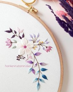 a close up of a embroidery on a hoop with scissors and flowers in the background