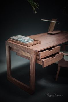 a wooden desk with two drawers and a phone on it's side, next to a potted plant