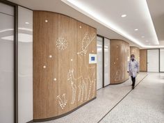 a person in a white coat walking down a hallway with wood paneling on the walls