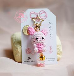 a keychain with a small pink bunny on it's side and a tag attached to it