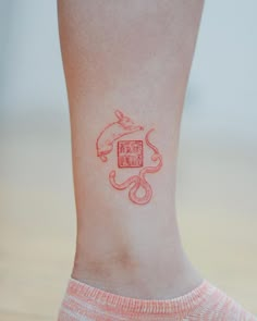 a woman's foot with a red tattoo on her left leg and an animal in the middle