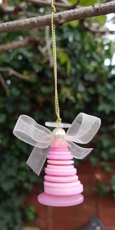 a pink and white ornament hanging from a tree