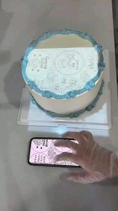 a person holding a cell phone in front of a cake