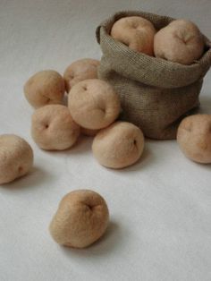 some apples are sitting in a bag and on the table next to them is several pieces of felt