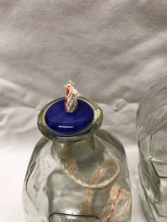 a glass jar with a rope wrapped around it and another container next to it on a white surface