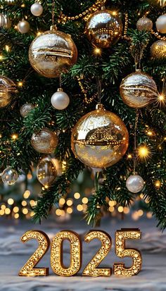 a christmas tree with gold ornaments and the number 205 on it in front of a snowy background