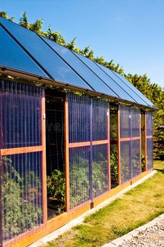 a small greenhouse with lots of plants growing on it's sides and the roof covered in solar panels