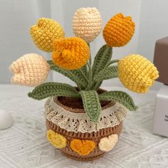 a crochet potted plant with yellow flowers in it sitting on a table