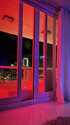 an open window with purple curtains and city lights in the background at night from outside