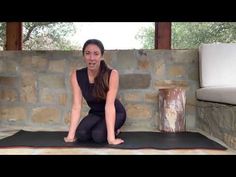 a woman sitting on top of a yoga mat in front of a stone wall and floor