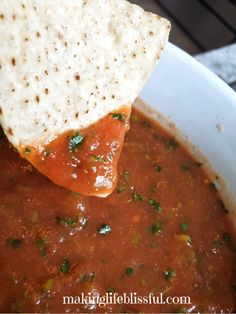 a tortilla chip being dipped with salsa