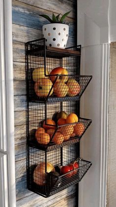 three wire baskets filled with fruit on top of a wall