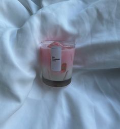 a pink candle sitting on top of a white sheet covered in sheets with a tag