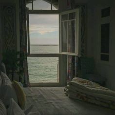 a bedroom with an open window overlooking the ocean