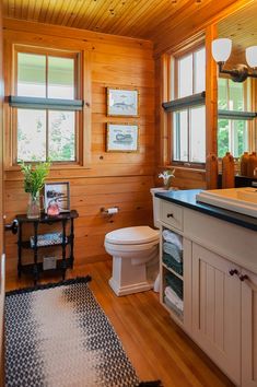 a bathroom with wooden walls and flooring, including a toilet in the center of the room