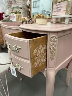 a pink dresser with gold trim and drawers on display at a home decor showroom