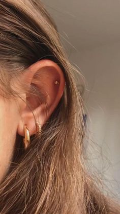 a close up of a person's ear with two gold hoops on it