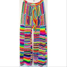 a multicolored knitted pants hanging on a hanger in front of a white wall