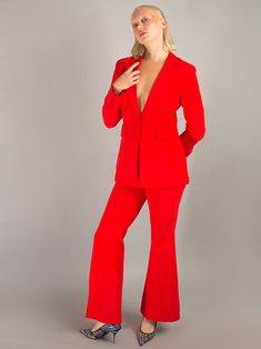 a woman in a red suit posing for the camera with her hands on her hips