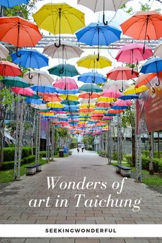 colorful umbrellas are hanging from the ceiling in an open area with text reading wonders of art'n'tatching