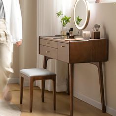 a person walking past a dressing table with a mirror and stool in front of it