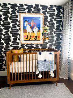 a baby crib in front of a black and white wallpaper with horse images on it