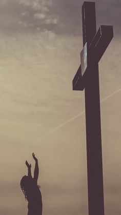 a person reaching up to the cross with their arms in the air and one hand raised