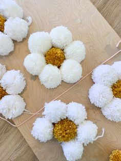 white and yellow pom - poms are tied to a string on the floor