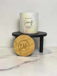 a candle sitting on top of a table next to a wooden coaster that says eaf