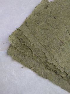 a pile of green paper sitting on top of a white sheet of waxy paper